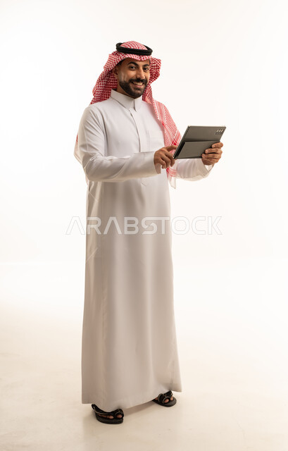 Saudi Man in Traditional Thobe Using Tablet