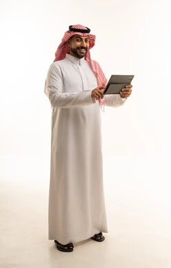 Saudi Man in Traditional Thobe Using Tablet