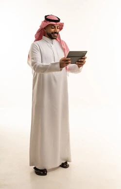 رجل سعودي بالثوب يستخدم جهاز لوحي رقمي