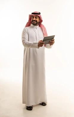 رجل سعودي بالثوب التقليدي يحمل جهاز لوحي رقمي