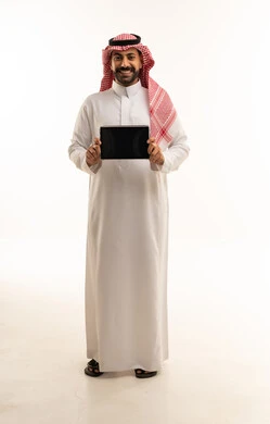 رجل سعودي بالثوب التقليدي يحمل جهاز لوحي ذكي