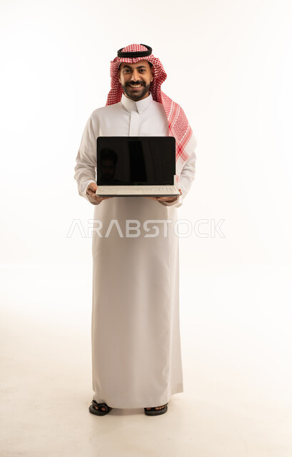 رجل سعودي يحمل كمبيوتر محمول بخلفية بيضاء