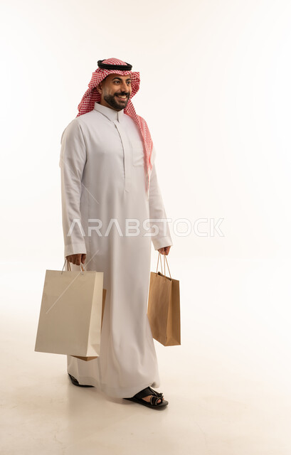 رجل سعودي يحمل حقائب تسوق على خلفية بيضاء