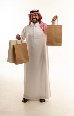 رجل سعودي يحمل أكياس تسوق ورقية على خلفية بيضاء