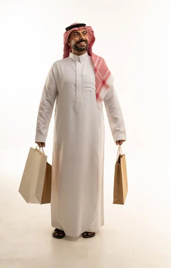 رجل سعودي يحمل حقائب تسوق بخلفية بيضاء