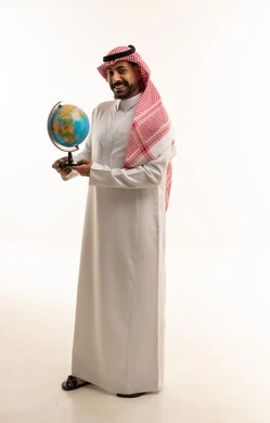 رجل سعودي يحمل مجسم الكرة الأرضية بالزي التقليدي