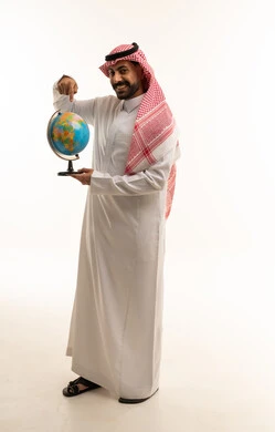 رجل سعودي بالثوب يشير إلى الكرة الأرضية بخلفية بيضاء