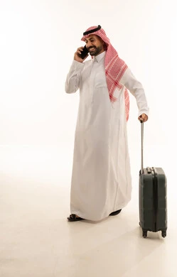 رجل سعودي مع حقيبة سفر يتحدث عبر الهاتف