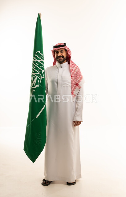 رجل سعودي يحمل العلم الوطني بخلفية بيضاء