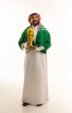 رجل سعودي يحمل كأساً ذهبياً مع العلم الوطني