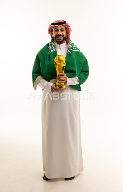 رجل سعودي يحمل كأساً ذهبياً مع العلم الوطني
