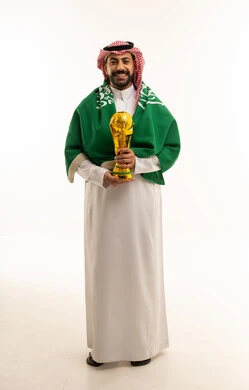 رجل سعودي يحمل كأساً ذهبياً مع العلم الوطني