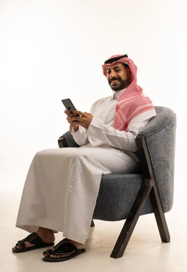 رجل سعودي بالزي التقليدي يستخدم الهاتف الذكي