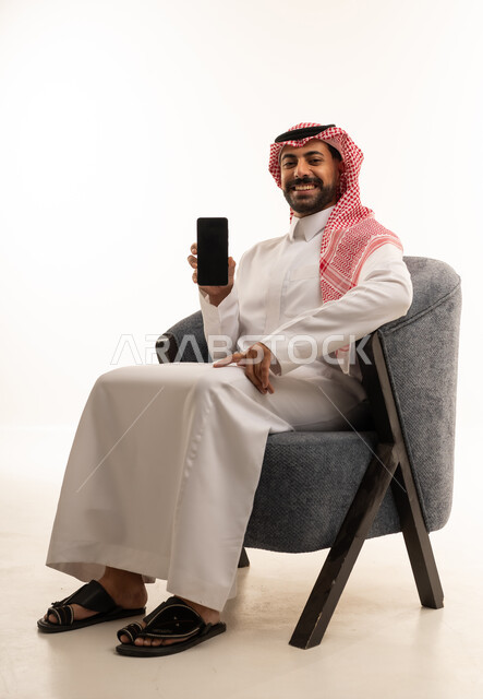 رجل سعودي يمسك هاتف ذكي بشاشة فارغة