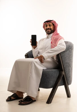 رجل سعودي يمسك هاتف ذكي بشاشة فارغة