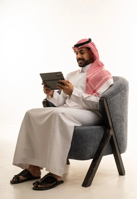 Saudi Man in Traditional Thobe Using Digital Tablet