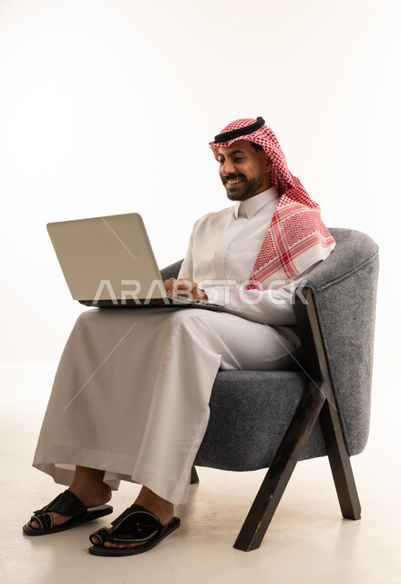 Saudi Man in Traditional Thobe Using Laptop