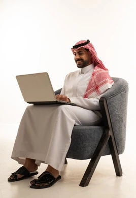 Saudi Man in Traditional Thobe Using Laptop
