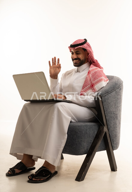 رجل سعودي يستخدم اللابتوب لمكالمة فيديو على خلفية بيضاء