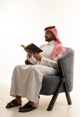 Saudi Man in Traditional Thobe Reading a Book