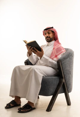 رجل سعودي بالثوب التقليدي يقرأ كتاباً