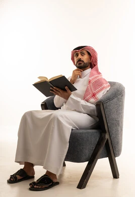 Saudi Man in Traditional Thobe Reading a Book