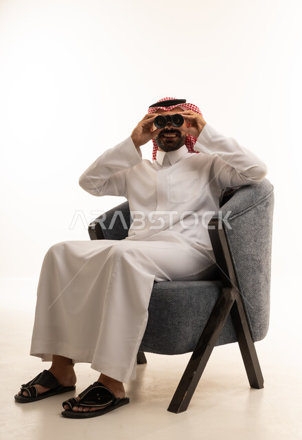 Saudi Man in Traditional Thobe Using Binoculars