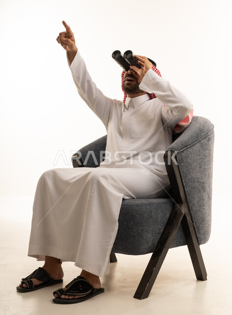 رجل سعودي مع منظار يشير للأعلى خلفية بيضاء