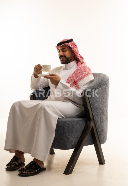 رجل سعودي بالزي التقليدي يشرب القهوة