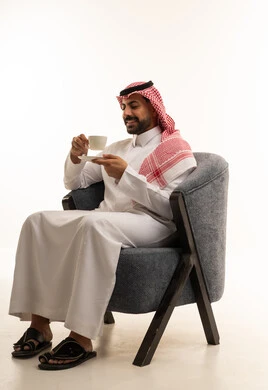 رجل سعودي بالزي التقليدي يشرب القهوة