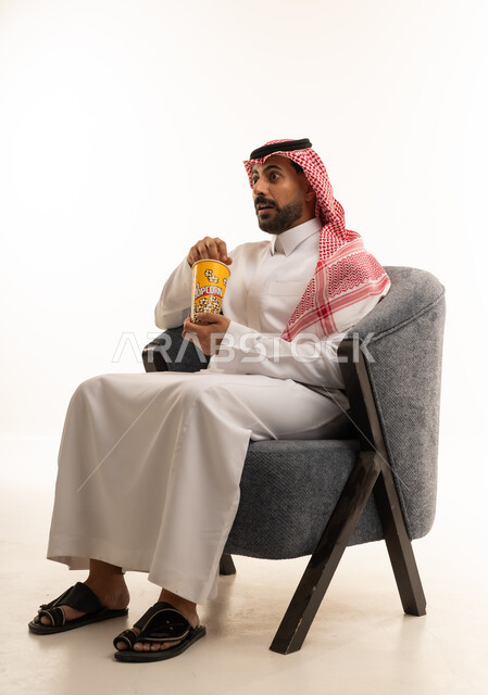 رجل سعودي يشاهد السينما مع علبة فشار