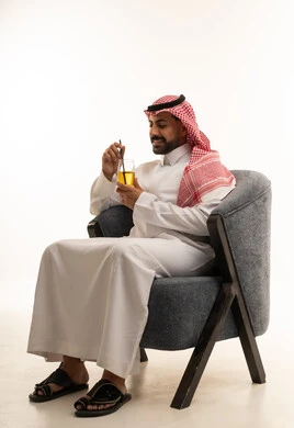 رجل سعودي بالزي التقليدي يجلس مع كوب عصير