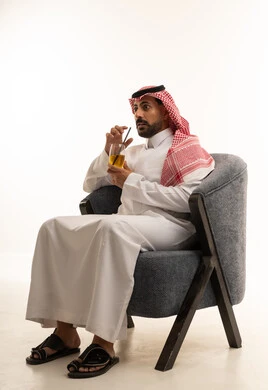 رجل سعودي بالزي التقليدي يجلس مع كوب عصير