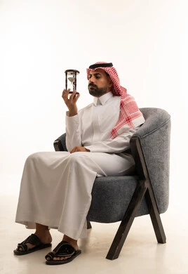 Saudi Man Holding Hourglass in Armchair Studio Shot