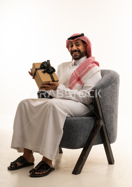 Saudi Man Holding Gift Box in Traditional Attire