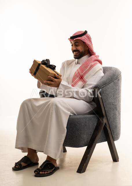 رجل سعودي بالثوب التقليدي يحمل صندوق هدايا