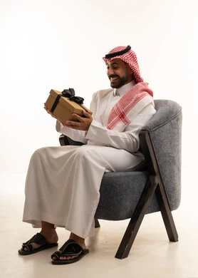 رجل سعودي بالثوب التقليدي يحمل صندوق هدايا