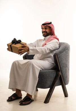رجل سعودي بالزي التقليدي يمسك صندوق هدايا
