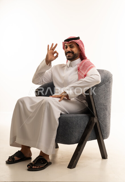رجل سعودي بالثوب التقليدي يشير بعلامة التمام