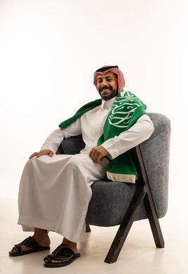 Saudi Man with Flag Sitting in Armchair Studio