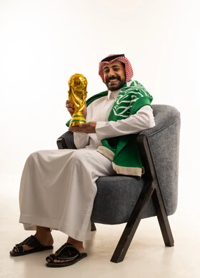 رجل سعودي بالزي التقليدي يحمل كأس العالم الذهبي