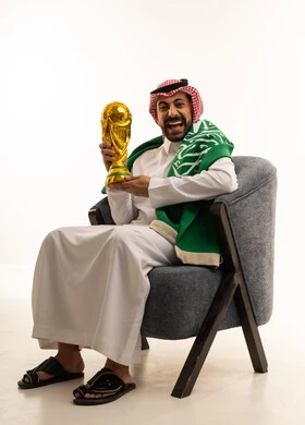 رجل سعودي يحمل كأس كرة قدم ذهبي مع العلم
