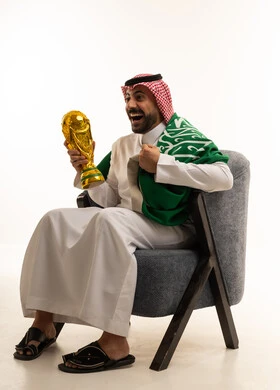 Saudi Man Celebrating with Football Trophy and Flag