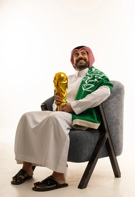 رجل سعودي يحمل كأس ذهبي مع العلم الوطني
