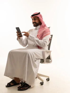 رجل سعودي بالزي التقليدي يستخدم الهاتف الذكي