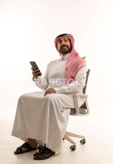 رجل سعودي بالثوب والشماغ يستخدم الهاتف الذكي