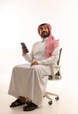 رجل سعودي بالثوب والشماغ يستخدم الهاتف الذكي