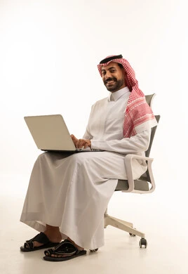 رجل سعودي يستخدم الحاسوب المحمول على كرسي مكتب