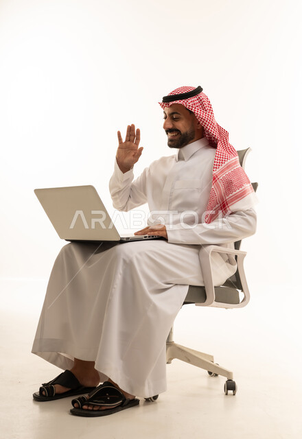 رجل سعودي يلوح لجهاز الكمبيوتر على كرسي مكتب