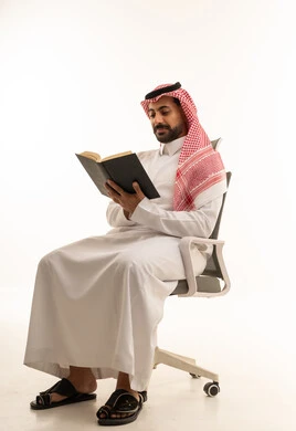 رجل سعودي بالزي التقليدي يقرأ كتاباً في الاستوديو
